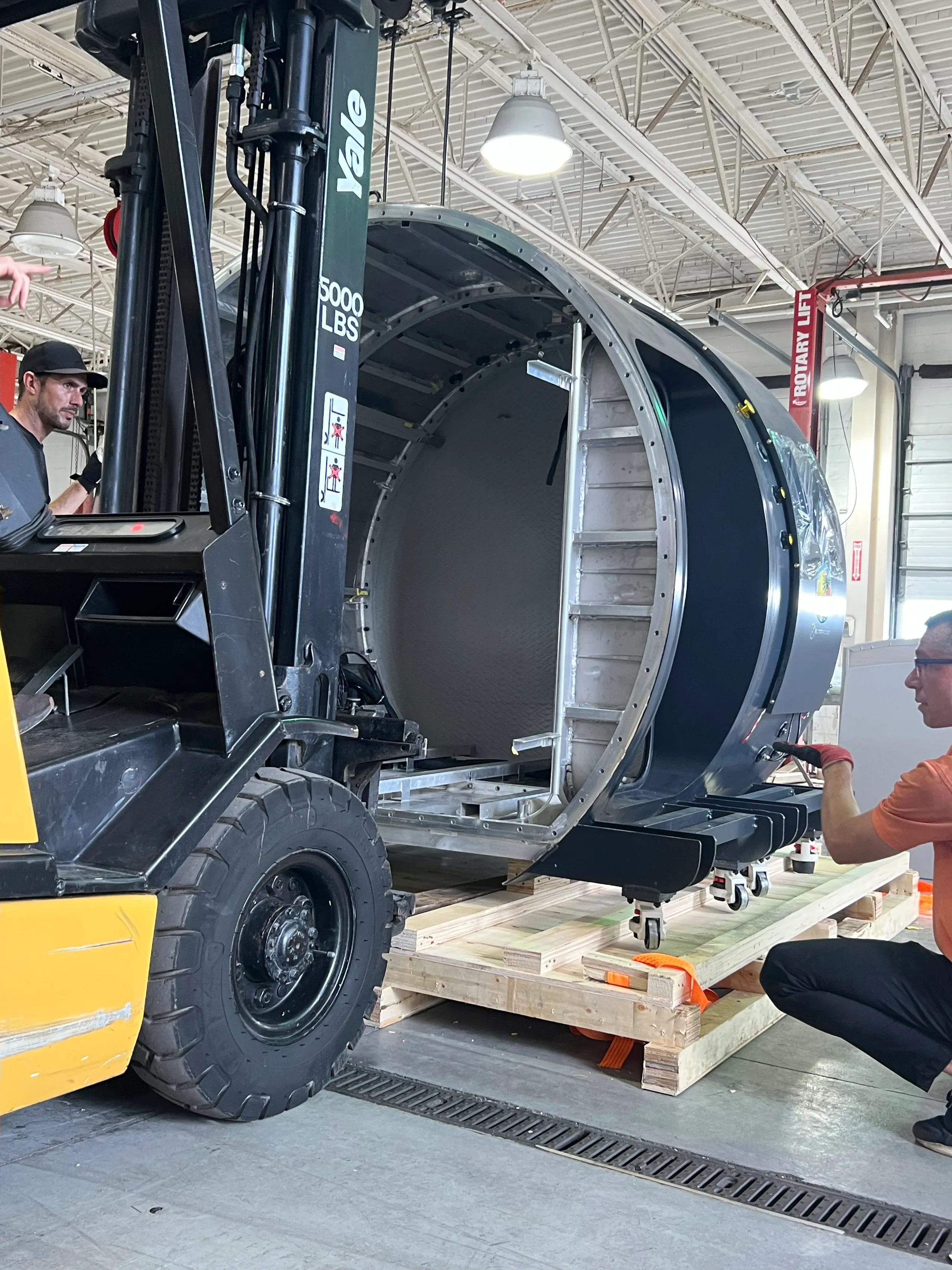 A forklift lifting a Superhuman hard-shell chamber off its pallet in the warehouse