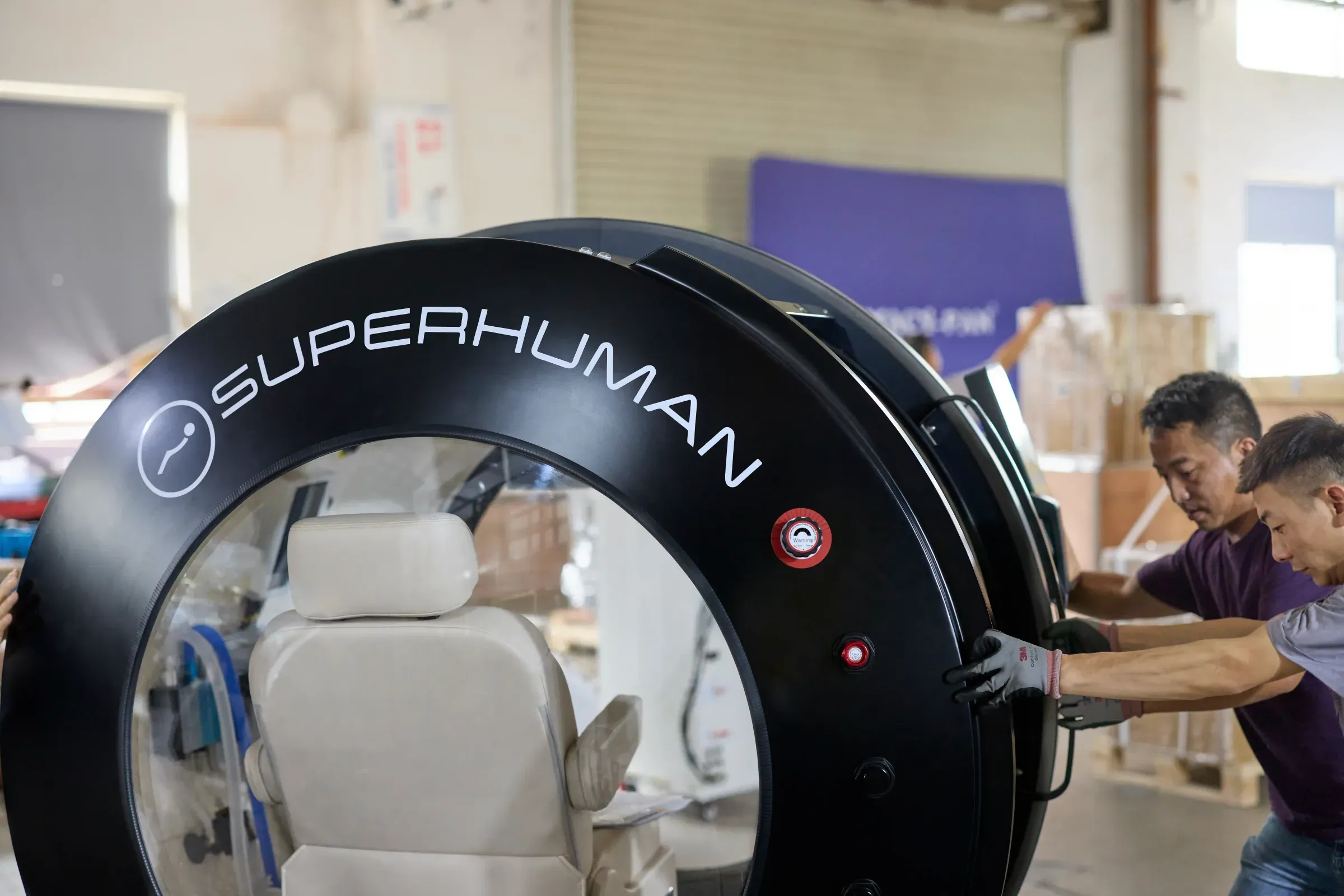 Technicians positioning a Superhuman X hyperbaric chamber during final assembly